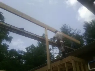 Carpenter setting a ridge beam over a new addition frame — Ice Dam Removal by Roofing Brothers in Middleboro