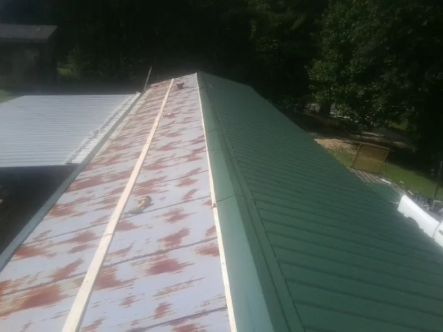 Old rusted panels beside newly installed green metal roofing — Wind Damage Roof Repair by Roofing Brothers in Middleboro