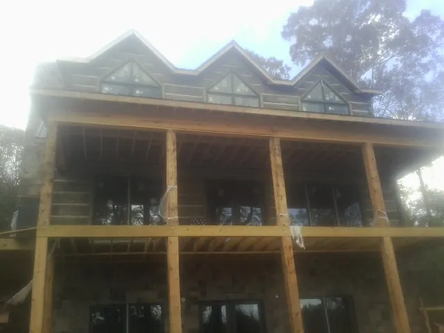 Dormers and porch framing on a large log home under construction — Roof Coating work by our crew in Middleboro