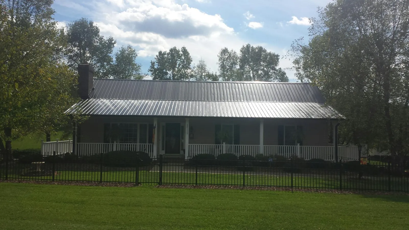 Gray metal roof on a brick ranch with a full width front porch — Gutter Guard Installation work by our crew in Middleboro