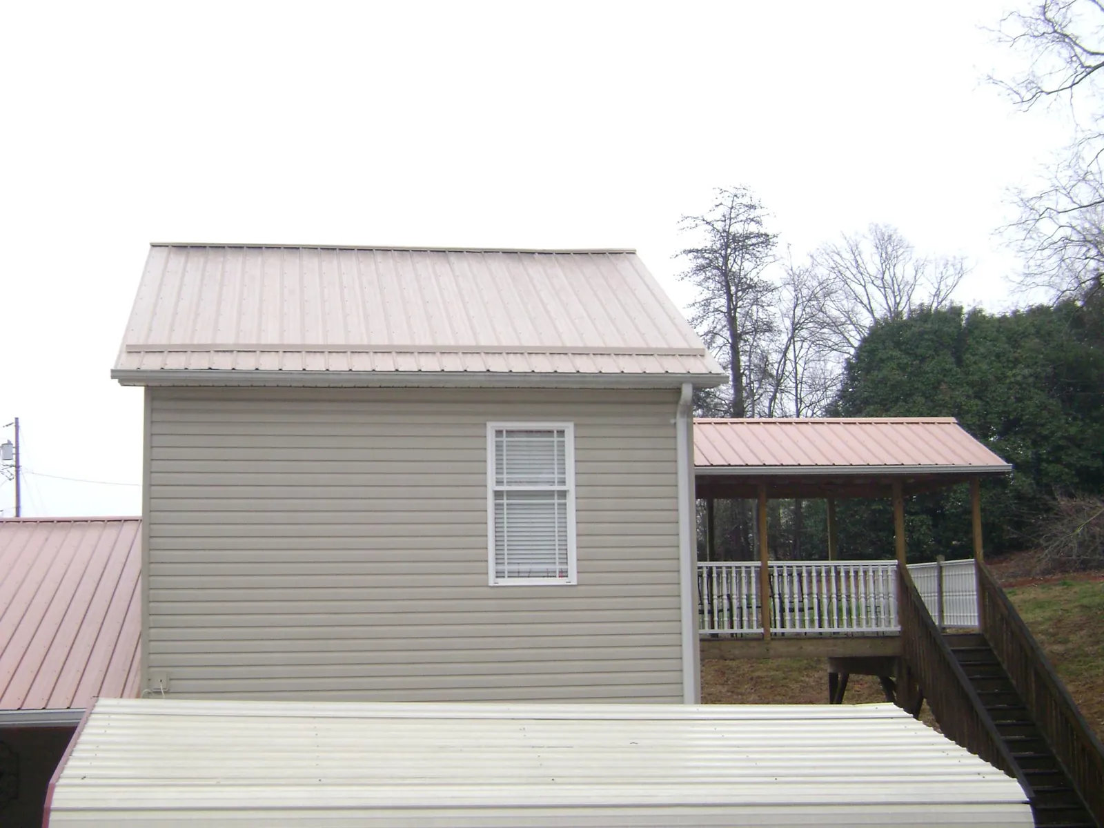 Tan metal roofs on a two story addition and attached porch, from a Roof Replacement job in Middleboro