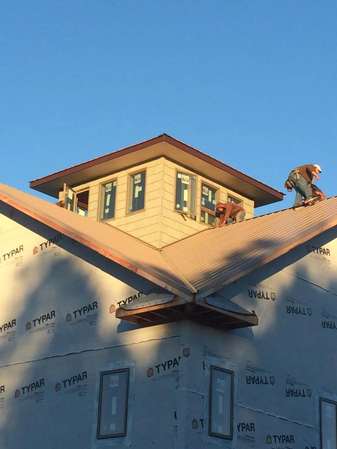 Roofers working around a rooftop cupola on a new metal roof at sunset — Roof Waterproofing in Middleboro by Roofing Brothers